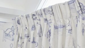 The curtains are white with a blue nautical pattern featuring boats, ships, and anchors. The rod is white and appears to be curved.