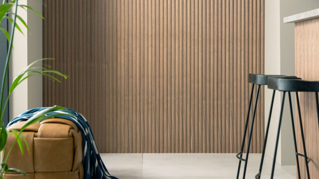 The wall is covered in a vertical wood-panelled design, adding a touch of warmth and texture to the space. The rest of the kitchen seems to be a neutral colour, with light grey countertops and a sleek white backsplash.