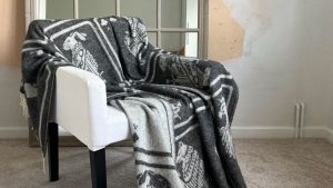 A cosy grey throw blanket with a playing card pattern draped over a white armchair.