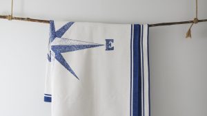 A white blanket with a nautical theme hangs from a branch.