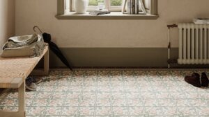A brightly lit entryway features patterned floor tiles in muted pink, grey, and cream, arranged in repeating floral and geometric designs.