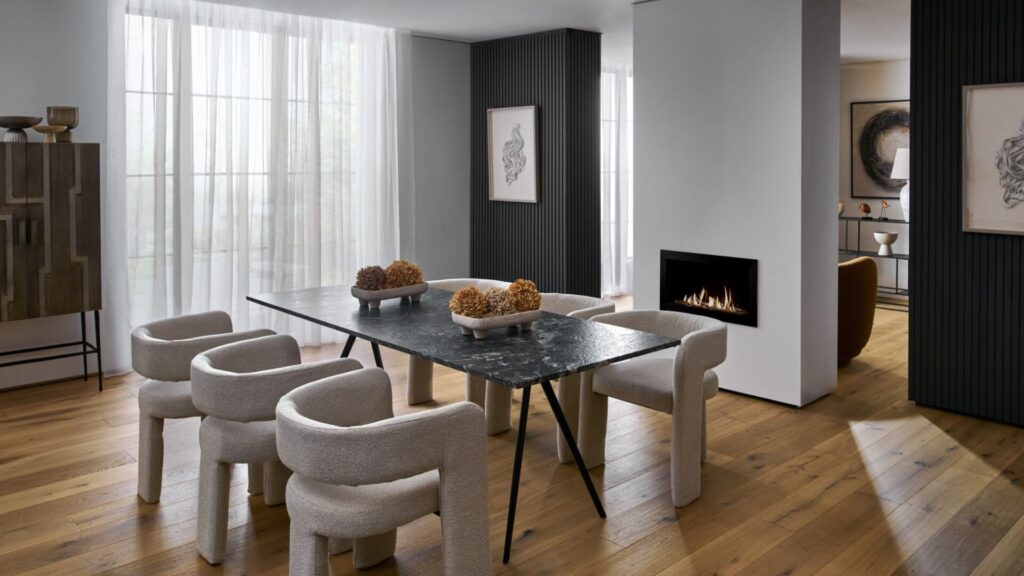 The flooring is a light-coloured wood, arranged in planks, which grounds the space and adds warmth. The room feels sophisticated and modern with a focus on clean lines, varied textures, and a neutral colour palette.
